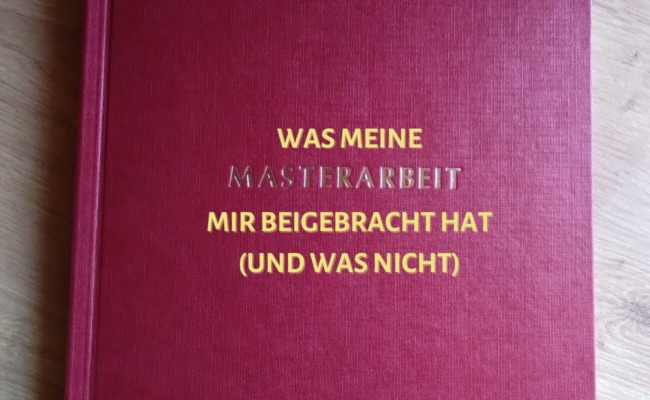 Eine Masterarbeit mit weinrotem Hardcover liegt auf einer Tischplatte. Darauf steht "Was meine Masterarbeit mir beigebracht hat (und was nicht)" in ockerfarbenen Großbuchstaben, wobei das Wort "Masterarbeit" in den Buchdeckel geprägt ist.
